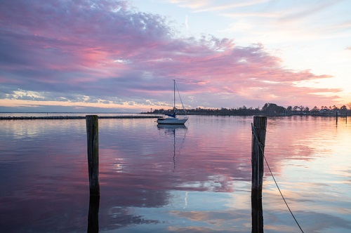 See the sunset by water on a sailboat in North Carolina