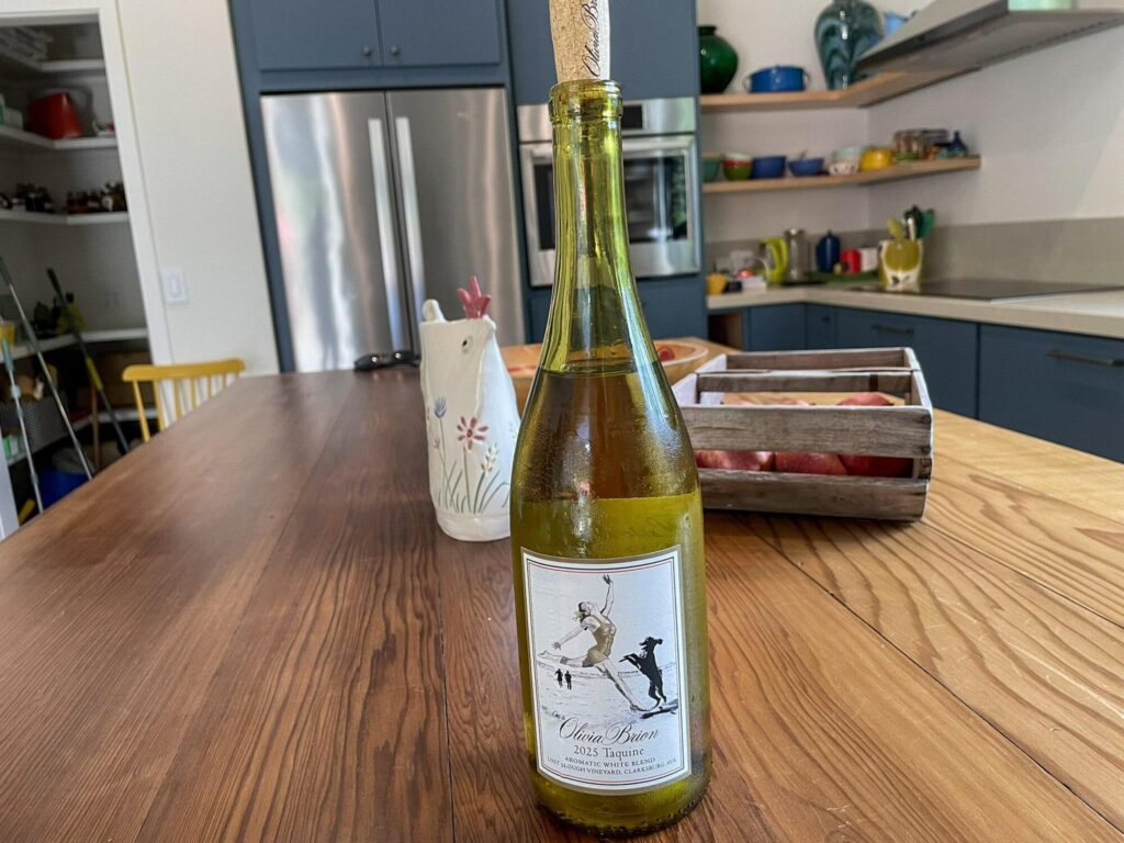 A bottle of 2025 Taquine white blend from Olivia Brion with its illustrated label